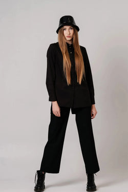 Model wearing a black long-sleeve collared button-front shirt with black trousers and boots