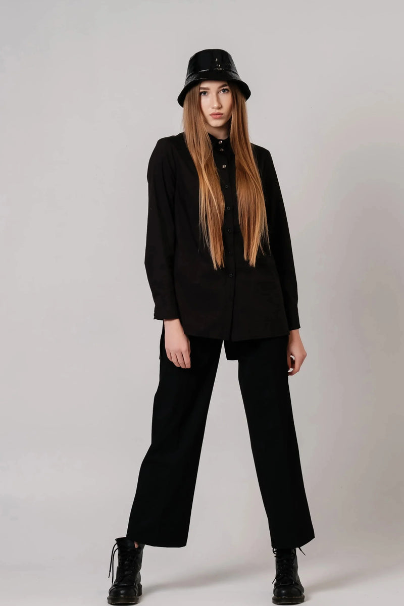 Model wearing a black long-sleeve collared button-front shirt with black trousers and boots