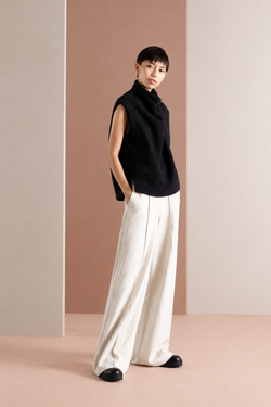Three-quarter view of a model wearing a black sleeveless high-neck vest