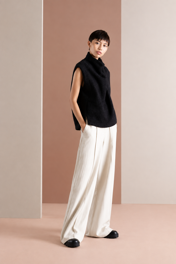 Three-quarter view of a model wearing a black sleeveless high-neck vest