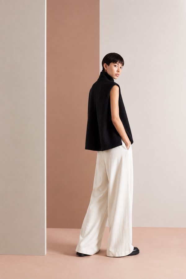 Rear three-quarter view of a model wearing a black sleeveless high-neck vest