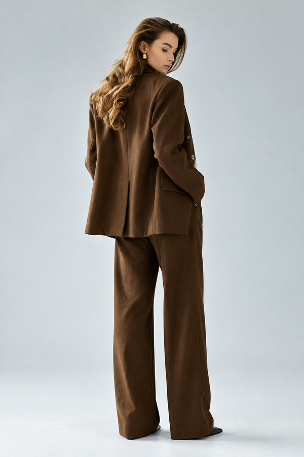 Rear three-quarter view of a model wearing a chocolate brown blazer and matching trousers