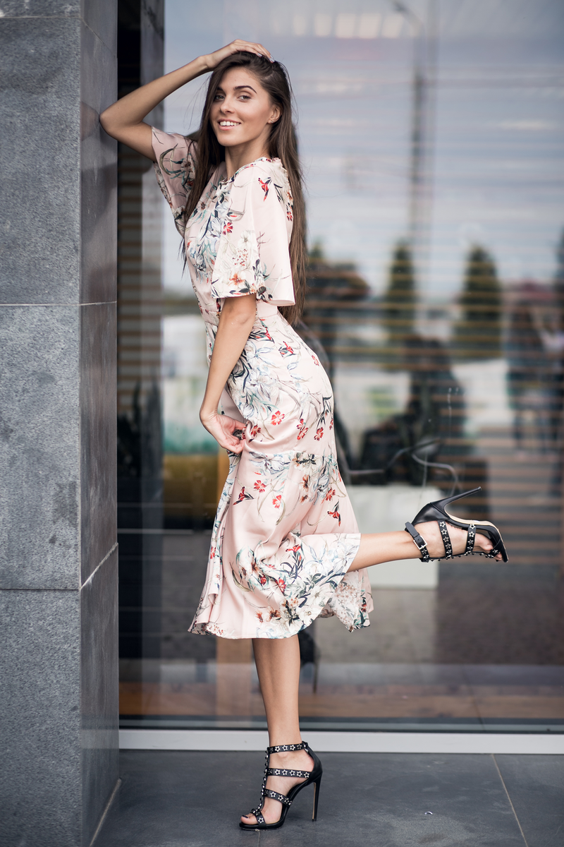 Model wearing a blush pink floral midi dress in an angled view