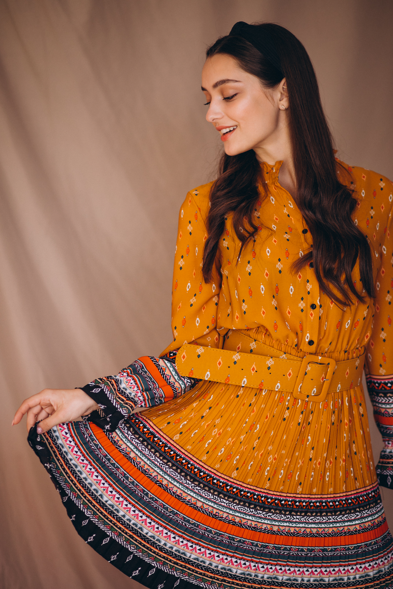 Side view of a mustard orange printed belted dress with patterned border detailing