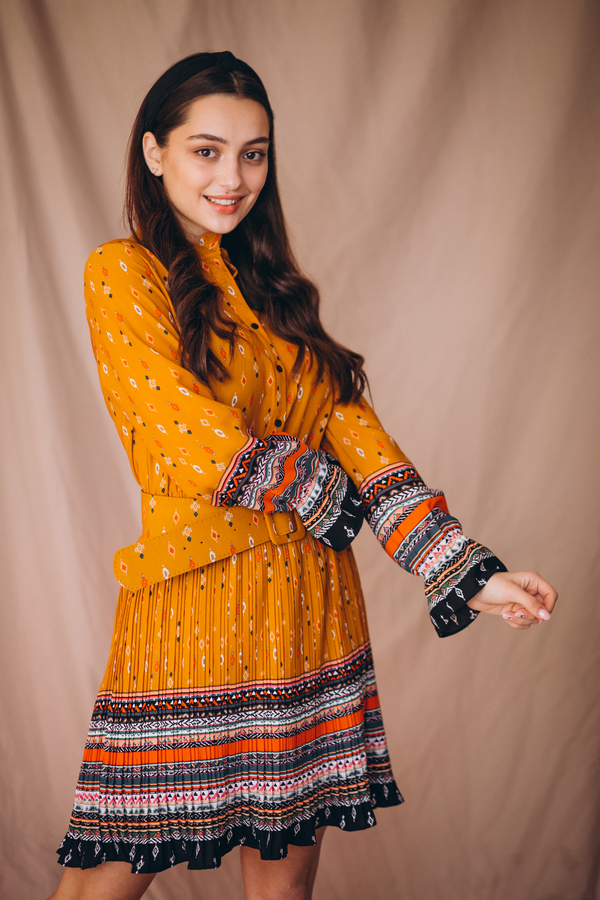 Angled view of a mustard orange printed long-sleeve dress with a waist belt